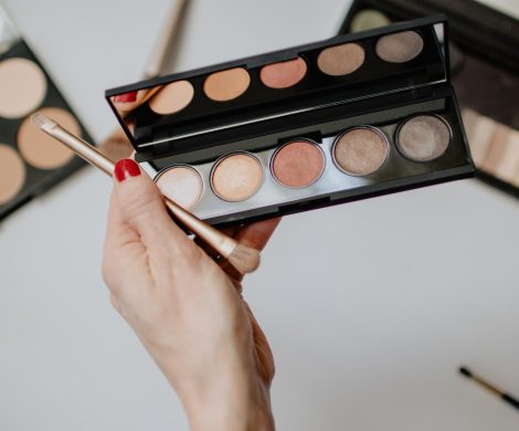 person holding makeup brush with makeup palette